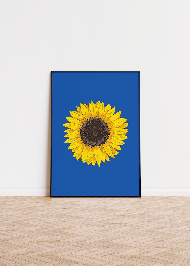 May include: A framed print of a yellow sunflower with a dark brown center on a bright blue background.