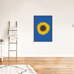 May include: A framed print of a yellow sunflower on a blue background.