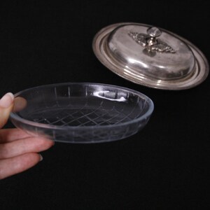 May include: A silver butter dish with a glass base. The lid has a decorative knob and a raised design.