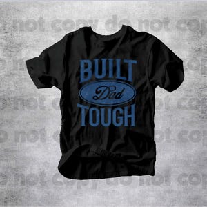 May include: Black t-shirt with the words "BUILT Dad TOUGH" in blue lettering. The text is arranged in a stacked format, with "Dad" inside a blue oval. The shirt has short sleeves and a crew neck.