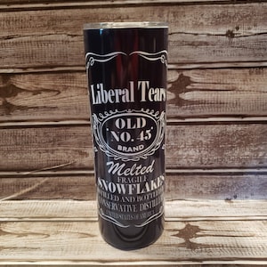 May include: A black stainless steel tumbler with a white design that reads "Liberal Tears Old No. 45 Brand Melted Fragile Snowflakes Distilled and Bottled Conservative Distillery United States of America".