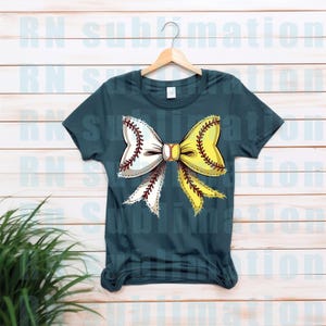 May include: A teal blue t-shirt with a white and yellow softball bow. The bow is made of two softballs with red stitching. The bow is centered on the shirt.