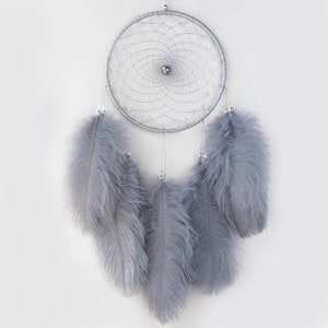 May include: A silver dream catcher with gray feathers. The dream catcher has a beaded border and a silver bead in the center.