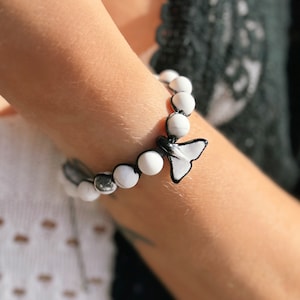 Può includere: Bracciale con perline bianche con un ciondolo a farfalla bianco e nero. Il bracciale presenta perline bianche rotonde e una perlina di accento color argento. Il ciondolo a farfalla è nero con dettagli bianchi. Un accessorio elegante.
