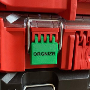 May include: A stack of red toolboxes with black accents. The top toolbox has a green latch with the word "ORGANIZR" printed on it.