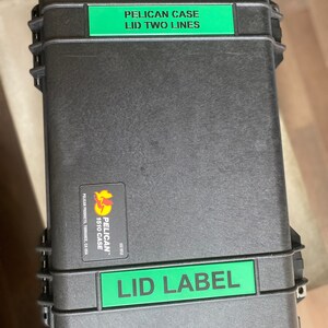 Op de afbeelding: Een zwarte Pelican 1510 koffer met groene labels met de tekst "PELICAN CASE LID TWO LINES" en "LID LABEL".