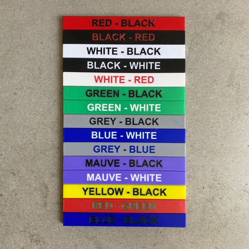 Op de afbeelding: Een set van 12 kleurgecodeerde labels met zwarte tekst. De labels lezen: Rood-Zwart, Zwart-Rood, Wit-Zwart, Zwart-Wit, Wit-Rood, Groen-Zwart, Groen-Wit, Grijs-Zwart, Blauw-Wit, Grijs-Blauw, Paars-Zwart, Paars-Wit, Geel-Zwart, Rood-Groen, Blauw-Zwart.