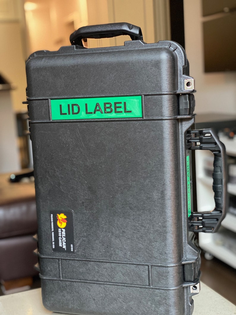 Pode incluir: Uma mala preta Pelican 1510 com uma pega e um autocolante verde "LID LABEL". A mala tem uma superf&iacute;cie texturizada e fechos seguros. Projetada para proteger equipamentos sens&iacute;veis.