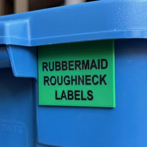 Peut inclure: Une étiquette verte avec du texte noir qui dit "Rubbermaid Roughneck Labels" sur un conteneur bleu.