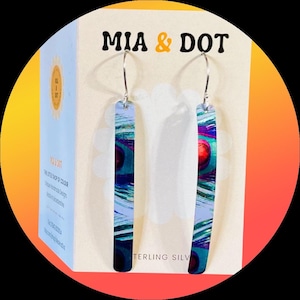 Pode incluir: Brincos longos e retangulares com um design de pena de pavão em tons de azul, verde e vermelho. Os brincos são suspensos por aros de prata. A embalagem apresenta o texto "MIA & DOT" e "STERLING SILVER".