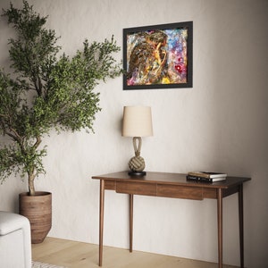 May include: A wooden desk with two drawers and a lamp with a rope base. A framed painting with a colorful abstract design hangs on the wall behind the desk.