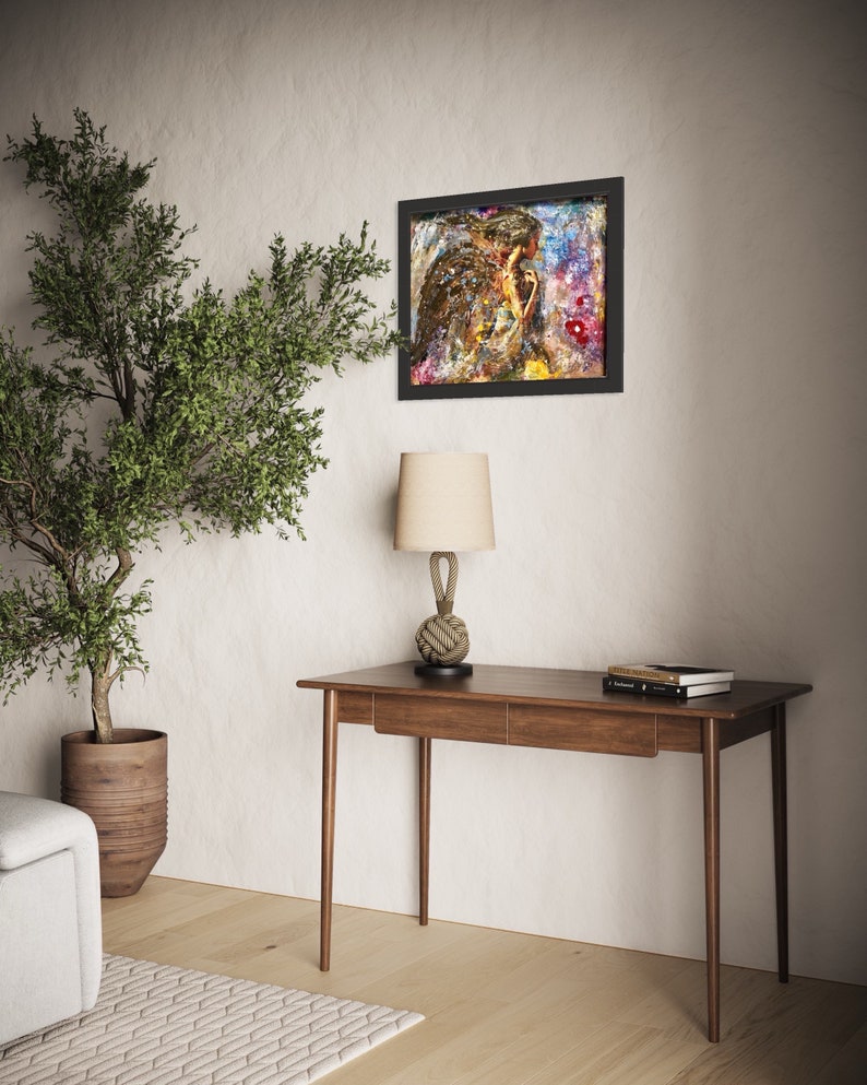 May include: A wooden desk with two drawers and a lamp with a rope base. A framed painting with a colorful abstract design hangs on the wall behind the desk.