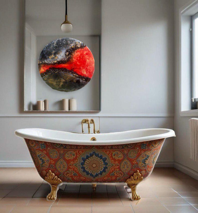 May include: A white clawfoot bathtub with a colorful patterned design. The bathtub has gold-colored feet and is in a bathroom with a mirror and a round abstract painting.