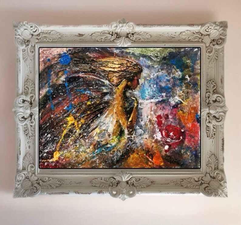 May include: A framed abstract painting of a woman with wings, with a colorful background of blue, yellow, red, and white paint splatters.