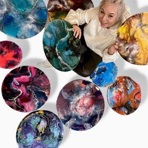 May include: A collection of ten round resin art pieces with abstract swirling patterns in various colors, including blue, green, purple, red, and yellow.