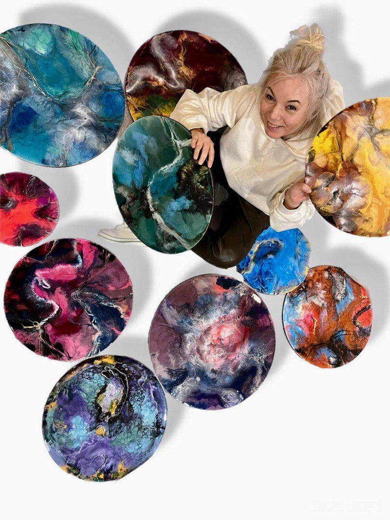 May include: A collection of ten round resin art pieces with abstract swirling patterns in various colors, including blue, green, purple, red, and yellow.