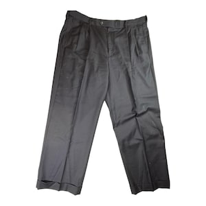 Pode incluir: Um par de calças cinza escuro com pregas. As calças têm fecho de botão e zíper, presilhas para cinto e dois bolsos frontais. As bainhas estão viradas para cima. O tecido parece ser de peso médio.