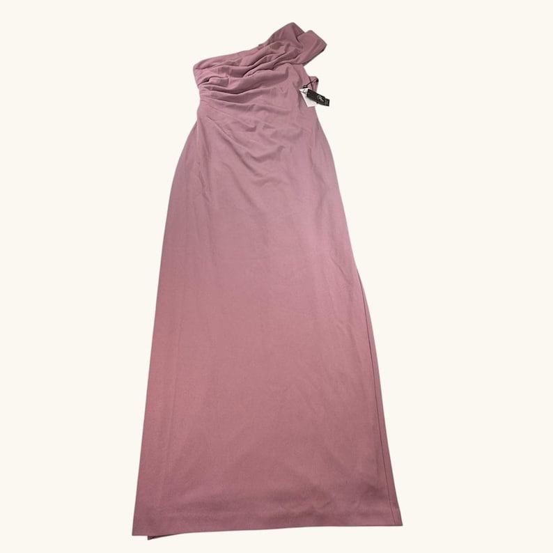 Puede incluir: Un vestido largo asim&eacute;trico rosa empolvado. El vestido presenta un escote drapeado y una falda larga y fluida. Una etiqueta est&aacute; adjunta. El vestido est&aacute; hecho de una tela suave y ligera.