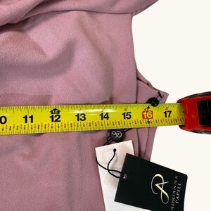 Puede incluir: Vestido rosa empolvado con una cinta m&eacute;trica que muestra una medida de 40,6 cm. El vestido tiene botones negros y una etiqueta de Adrianna Papell.