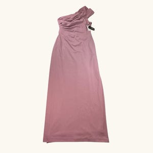Puede incluir: Un vestido largo asim&eacute;trico rosa empolvado. El vestido presenta un corpi&ntilde;o fruncido y una falda fluida. Una etiqueta est&aacute; adherida al hombro. El vestido est&aacute; hecho de una tela suave y ligera, ideal para una ocasi&oacute;n especial.