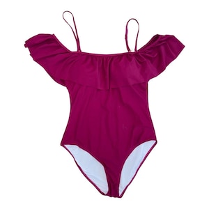May include: A magenta one-piece swimsuit with a ruffled, off-the-shoulder design. It has thin, adjustable straps and a white interior lining. The swimsuit's bottom has a high-cut leg opening. The measurements are in centimetres.