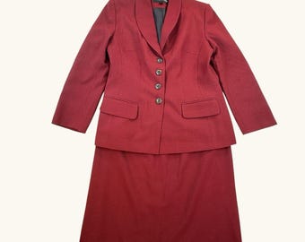May include: A two-piece red suit, featuring a blazer with three buttons and two front pockets, paired with a matching knee-length skirt. The suit has a classic design, suitable for professional or formal settings.