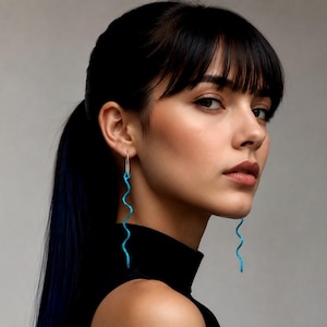 May include: A woman wearing a black turtleneck top with long, wavy, turquoise earrings. The earrings are a bright, eye-catching color and hang down from the earlobes.