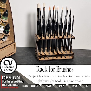 May include: A brown wooden brush rack with multiple vertical slots holding various black-handled paint brushes. The rack is designed for 3mm materials and includes text labels: CV Creative Vector, Rack for Brushes, Project for laser cutting for 3mm materials, Lightburn / xTool Creative Space, XCS, LBRN, SVG, PDF, DXF, AI.