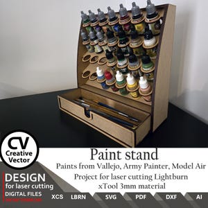 May include: A wooden paint stand with multiple levels to hold paint bottles and a drawer for brushes. The stand is designed for laser cutting and features the text "Paint stand". The stand is made of 3mm material.