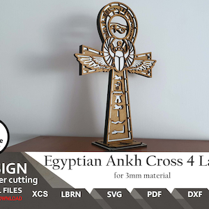 May include: A laser cut wooden model of an Egyptian Ankh cross with four layers. The cross is made of brown wood and has a white design. The cross is 3mm thick and is suitable for laser cutting.