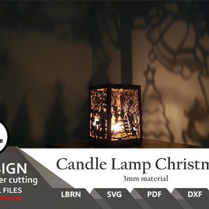 Könnte beinhalten: Eine Holz-Kerzenlampe mit Weihnachtsmotiv. Die Lampe ist zum Laserschneiden geeignet und 3 mm dick. Die Lampe ist angezündet und wirft einen Schatten einer Weihnachtsszene an die Wand hinter ihr.