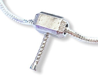 May include: A silver charm bracelet with a silver Mjolnir charm. The charm is a detailed replica of Thor's hammer.