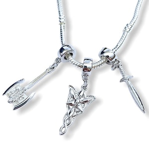 May include: A silver charm bracelet with three charms: a sword, an axe, and a stylized symbol with a star and a swirl.