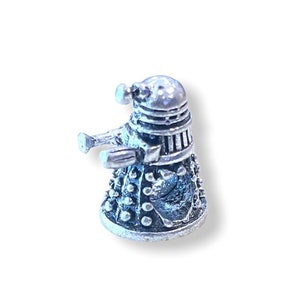 May include: A silver-colored, detailed miniature figurine of a Dalek, a fictional robot from the British science fiction television series Doctor Who.