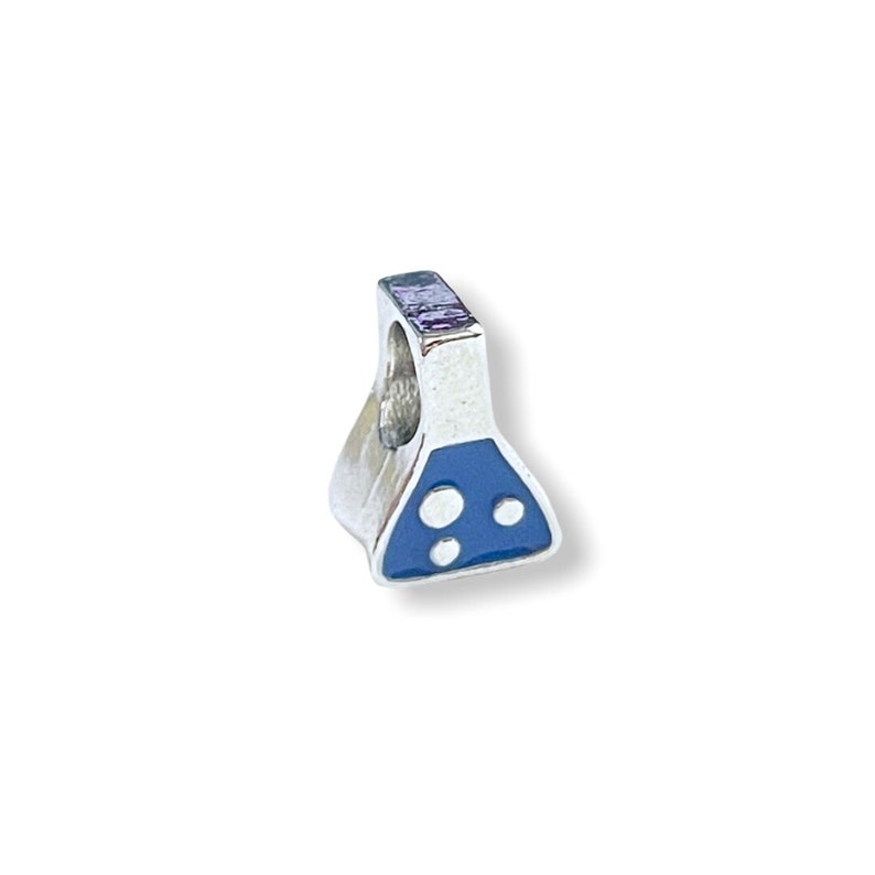 May include: A silver-colored charm in the shape of a laboratory flask. The flask has a blue enamel design on the bottom with three white circles. The charm has a hole at the top for attaching to a bracelet or necklace.