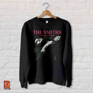 May include: Black sweatshirt with a graphic print of The Smiths album cover "The Queen Is Dead". The album title is in pink text.