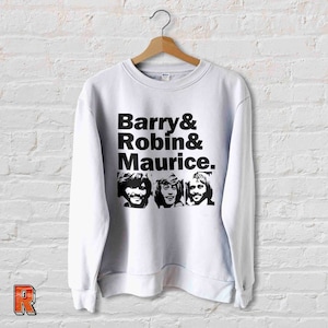 May include: White sweatshirt with a black print of the names "Barry & Robin & Maurice" and three black and white photos of men.