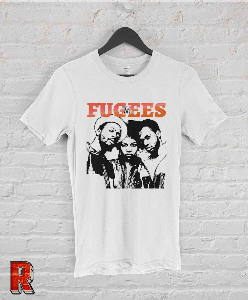 May include: White t-shirt with a black and white image of the hip-hop group The Fugees. The band's name is printed in red letters above the image.