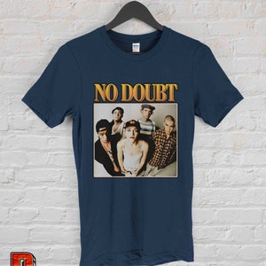 May include: A navy blue t-shirt with a vintage-style graphic of the band No Doubt. The graphic features a photo of the band members, including Gwen Stefani, Tony Kanal, Adrian Young, Tom Dumont, and Eric Stefani.