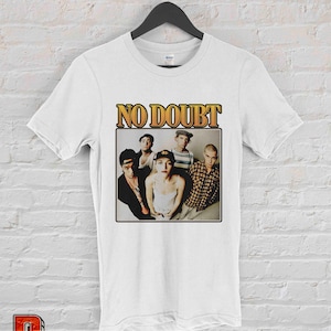 May include: White t-shirt with a vintage-style graphic of the band No Doubt. The graphic features a photo of the band members, including Gwen Stefani, in black and white.