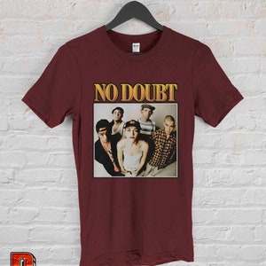 May include: A maroon t-shirt with a vintage-style image of the band No Doubt. The image features the band members in a group photo, with the band's name in gold lettering above them.