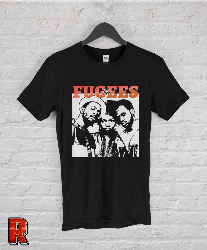 May include: Black t-shirt with a white graphic of the hip-hop group The Fugees. The group members are shown in black and white, with the band name in red and orange.