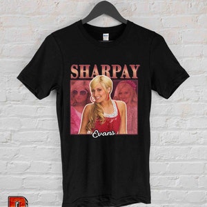 May include: Black t-shirt with a vintage-style graphic of Sharpay Evans from the movie High School Musical. The graphic features a pink and red background with a picture of Sharpay Evans and the text "Sharpay Evans".