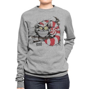 May include: A gray sweatshirt featuring a grinning Cheshire Cat illustration. The cat has a red and white striped tail and a large, toothy smile. The graphic is a whimsical design, perfect for fans of fantasy and literature.