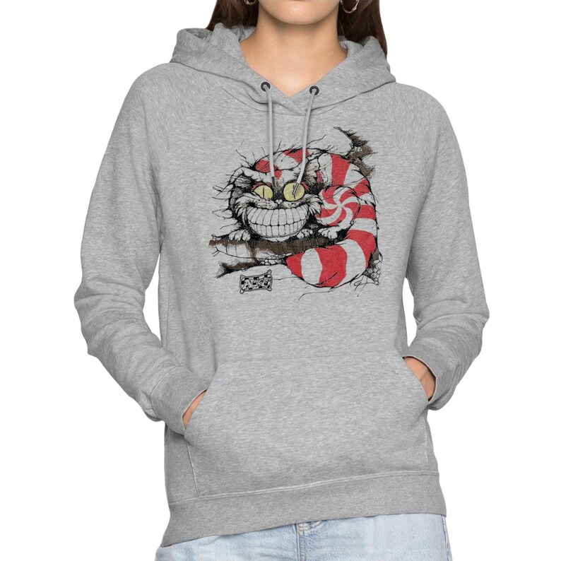 May include: A light gray hoodie featuring a graphic of the Cheshire Cat from Alice in Wonderland. The cat is depicted with a wide grin, striped tail, and red and white stripes. The hoodie has a drawstring hood and a kangaroo pocket.