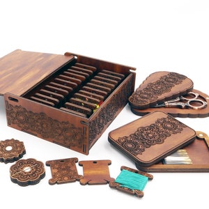 May include: A wooden sewing box with a hinged lid, containing compartments for needles, thread, and other sewing supplies. The box is decorated with intricate laser-cut designs.