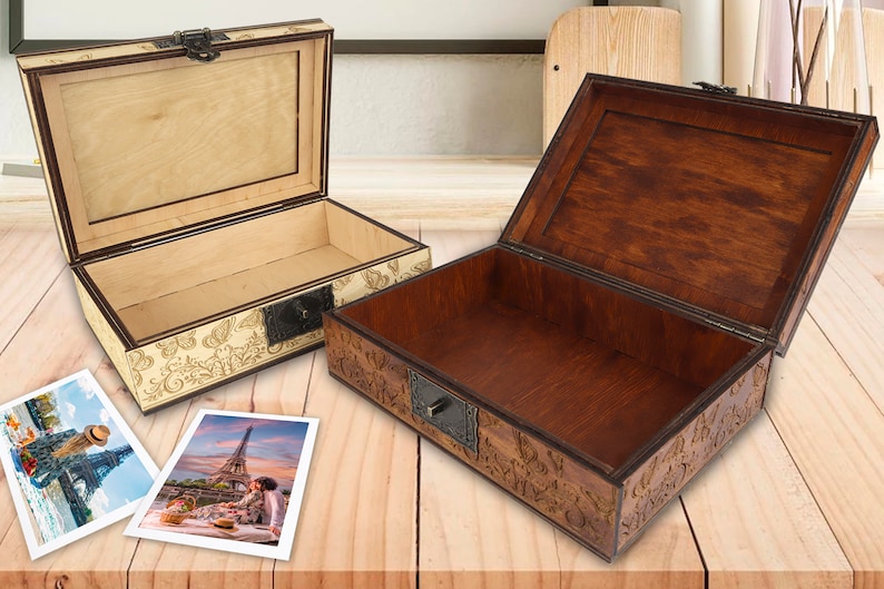 May include: Two wooden boxes with intricate carvings and brass accents. The boxes are open and empty, revealing the interior wood. The boxes are on a wooden surface.