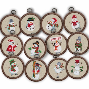 May include: A collection of twelve circular cross-stitch ornaments, each featuring a unique snowman design. The snowmen wear hats, scarves, and other winter accessories. The ornaments are framed in wooden hoops with a metal loop for hanging.