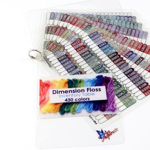 Könnte beinhalten: Ein transparenter Plastik-Organizer mit einem Ringbuch enthält einen Fächer mit farbcodierten Garnproben. Das Garn ist mit Nummern beschriftet. Eine kleinere Karte zeigt einen Regenbogen aus Garnfäden und den Text "Dimension Floss Inventory Table 430 colors".
