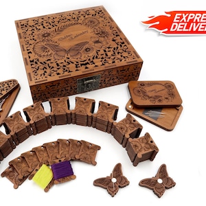 Pode incluir: Um kit de bordado de madeira com um design de borboleta. O kit inclui uma caixa de madeira, bobinas de fio, agulhas e um par de tesouras. A caixa é gravada com as palavras "Stitchery Essentials".